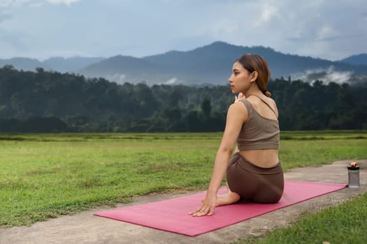 Asian woman sporty practicing yoga at public park outdoor stretching her body. Healthy active lifestyle.