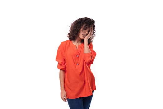 young tired caucasian lady with black curly hair dressed in an orange shirt thought.