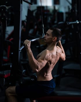 A man does a chest pulldown in the gym