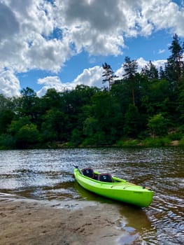 Kayak boat on the river Gauja, exploring nature, green kayak boat is on the bank of the river. High quality photo