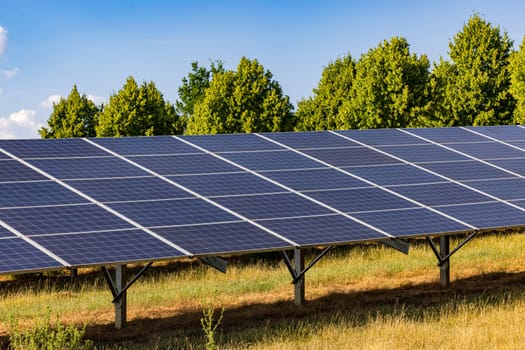 View along photovoltaic solar panels in an open space green energy generation plant, Germany