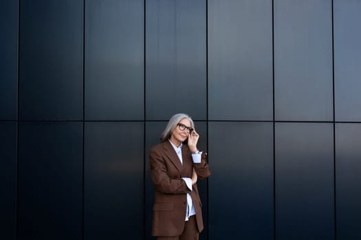 portrait of a well-groomed gray-haired middle-aged woman with a bob hairstyle dressed in a jacket and trousers. middle aged business concept.