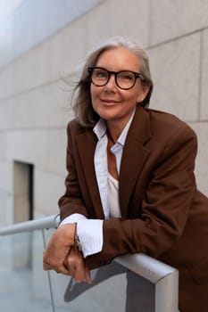 close-up portrait of a charming slim mature woman with gray hair in a stylish suit on the street.