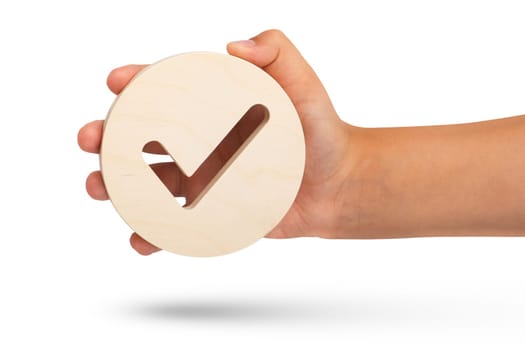 Isolate of hand holding check mark icon on white background. Closeup hand with wooden tick icon, right sign. copy space. Place for text. High quality photo