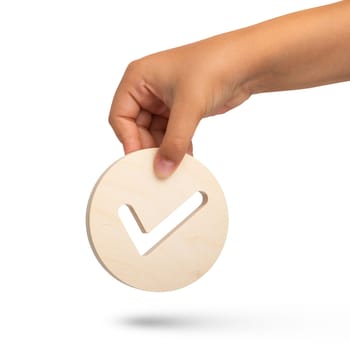 Isolate of hand holding check mark icon on white background. Closeup hand with wooden tick icon, right sign. copy space. Place for text. High quality photo