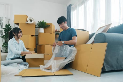 Young married couple moving into new home. They're unpacking or packing card boxes with their accessories.