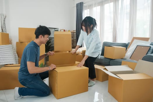 Young married couple moving into new home. They're unpacking or packing card boxes with their accessories. Moving to new house , new house owner concept.