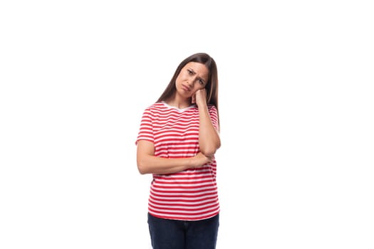 young upset sad european brunette woman dressed in a striped t-shirt on a white background.