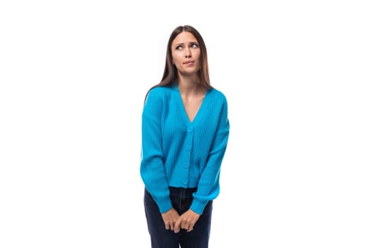 young pretty brunette lady dressed in a blue V-neck sweater on a white background with copy space.