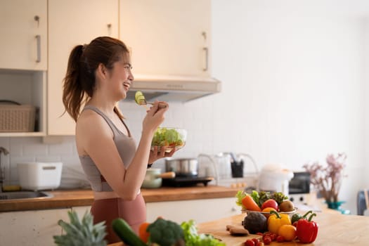 Young woman eat healthy food sitting in the kitchen.