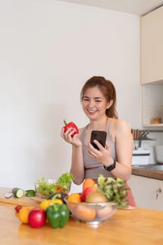 Happy female asian smile eating vegetables fruit and using smartphone, diet day weight counting calories. eating and health care concept.