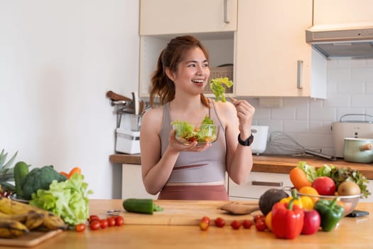 Young woman eat healthy food sitting in the kitchen.