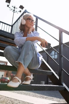 a well-groomed middle-aged woman with a bob haircut listens to music on a walk.