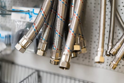 Closed up braided stainless steel texture of flexible hose arranged in row against white wall.