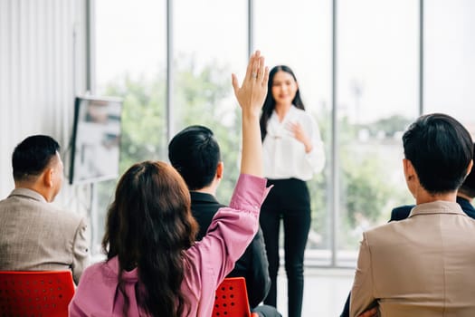 A large group in a seminar classroom raises their hands, actively participating and engaged in the discussion. The audience has the answer in this dynamic conference setting.