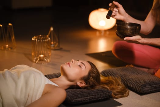 a girl lying on the floor relaxes to the sounds of a Tibetan bowl in the gym.