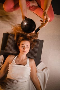 a girl lying on the floor relaxes to the sounds of a Tibetan bowl in the gym.