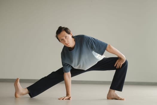 a man in a sports uniform does yoga in a fitness room. the concept of a healthy lifestyle.