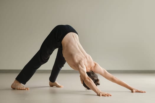 a man with a naked torso does yoga in the gym. the concept of a healthy lifestyle.