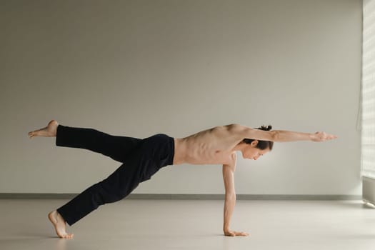 a man with a naked torso does yoga in the gym. the concept of a healthy lifestyle.