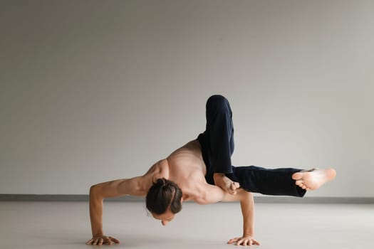 a man with a naked torso does yoga in the gym. the concept of a healthy lifestyle.