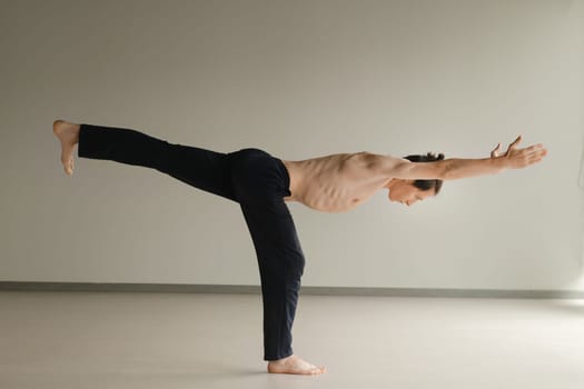 a man with a naked torso does yoga in the gym. the concept of a healthy lifestyle.