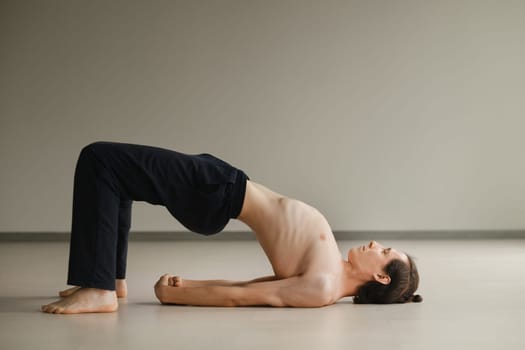 a man with a naked torso does yoga in the gym. the concept of a healthy lifestyle.