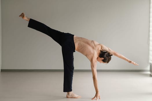 a man with a naked torso does yoga in the gym. the concept of a healthy lifestyle.