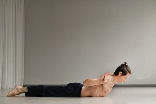 a man with a naked torso does yoga in the gym. the concept of a healthy lifestyle.