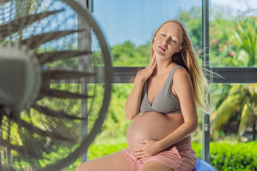 A pregnant woman seeks relief from an abnormal heatwave by using a fan, ensuring her comfort and well-being during sweltering conditions.