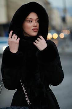 Muslim woman walking on an urban city street on a cold winter night wearing hijab with bokeh city lights in the background