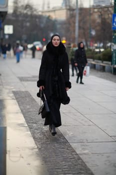 Muslim woman walking on an urban city street on a cold winter night wearing hijab with bokeh city lights in the background