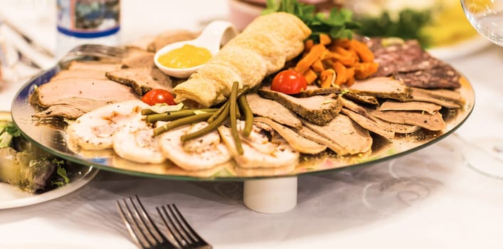 platter of sliced ham,salami and cured meat with vegetable decoration on festive table