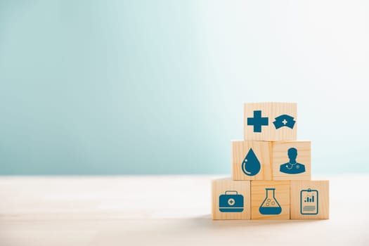Wooden cubes stacked as a pyramid, portraying healthcare and insurance concept. Topped with a medical insurance icon against white background, allowing Health Insurance communication.