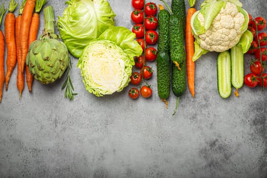 Fresh various organic vegetables arranged in line on rustic grey stone table top view copy space. Vegetarian food background, healthy vegetable ingredients with vitamins concept, diet and nutrition