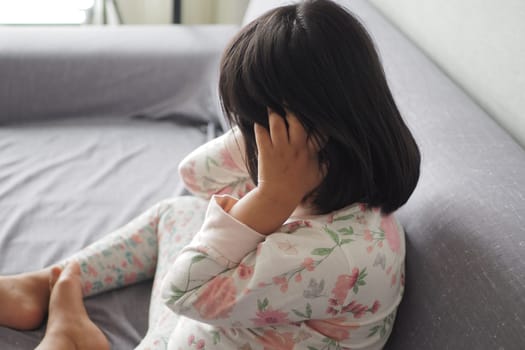 a upset child girl cover her face with hand .