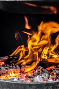 Burning coals and wood in a metal grill for frying meat and vegetables. Cooking on a campfire.