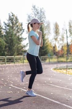 A young beautiful woman in sportswear plays sports at a local stadium. Exercise, jog and exercise at the beginning of the day. Healthy and active lifestyle.