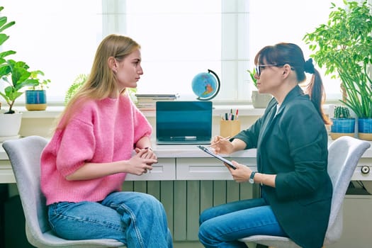 Female psychologist therapist working with young teen girl sitting in office. Teenage female student at therapy meeting with counselor. Psychology therapy psychotherapy youth mental health treatment