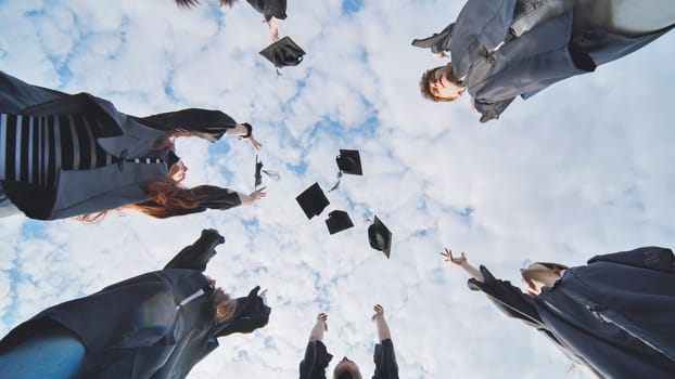 Joyful graduates stand in a circle and toss their caps up