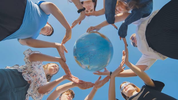 Young boys surround the globe of the world with their palms