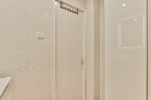 a bathroom with white tiles on the walls and shower stall in front of the door, there is a mirror above it