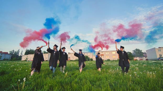 Students graduate with colored smoke walking through the meadow in the evening