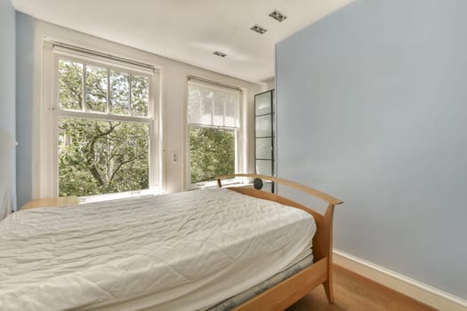 a bedroom with blue walls and white bedding, there is a large window in the room to the left