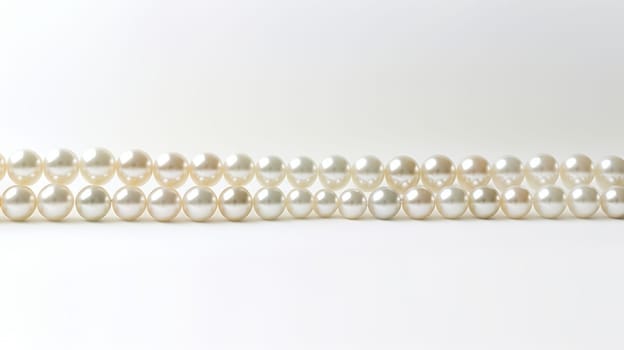 String of pearls on white background. White and round pearls with iridescence. Pearls decrease in size towards the ends. Perfect for themes of elegance, luxury and beauty. High quality photo