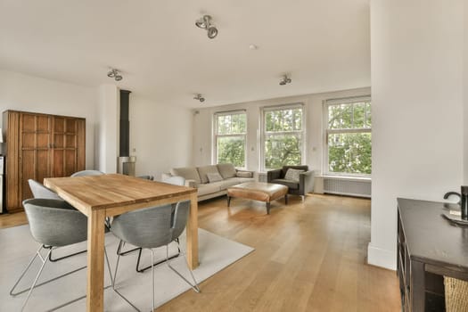 a living room with wood flooring and white walls, including a wooden dining table surrounded by two grey chairs