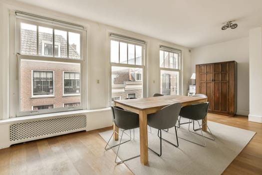 a dining table and chairs in a living room with large windows looking out onto the cityscaped area