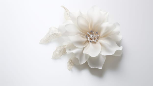 A white flower hair clip on a white background. The flower is made of fabric and has a pearl and rhinestone center. The petals are layered and have a slight sheen to them. The clip is attached to a white mesh ribbon. High quality photo