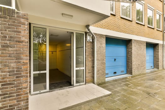 a brick building with two blue garage doors on the side and an open door at the other one is visible