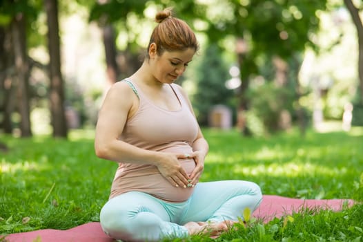 Prenatal yoga. Caucasian pregnant woman doing butterfly pose in the park